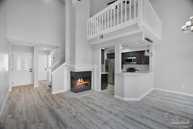 601 E Burgess Rd Unit J2, Pensacola, FL 32504 - unfurnished living room featuring a high ceiling, light wood-style floors, baseboards, a fireplace with flush hearth, and a sink
