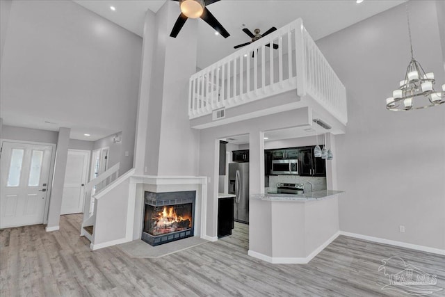 601 E Burgess Rd Unit J2, Pensacola, FL 32504 - kitchen featuring appliances with stainless steel finishes, a towering ceiling, wood finished floors, a ceiling fan, and a lit fireplace