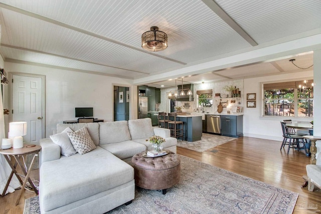 living area with a chandelier, light wood-type flooring, and baseboards