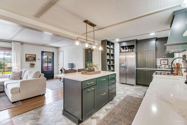 kitchen featuring a sink, stainless steel fridge with ice dispenser, open floor plan, and a center island