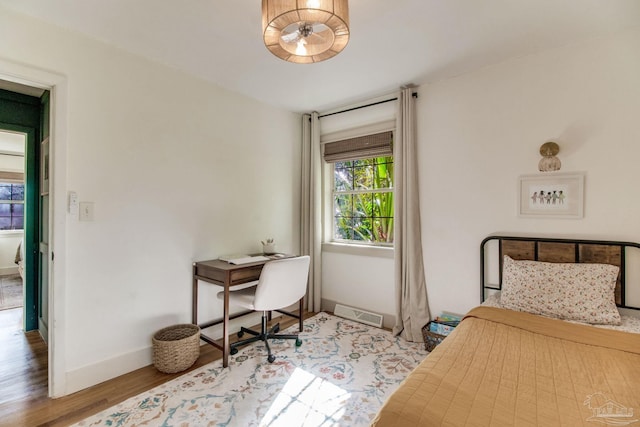 bedroom with visible vents, wood finished floors, and baseboards