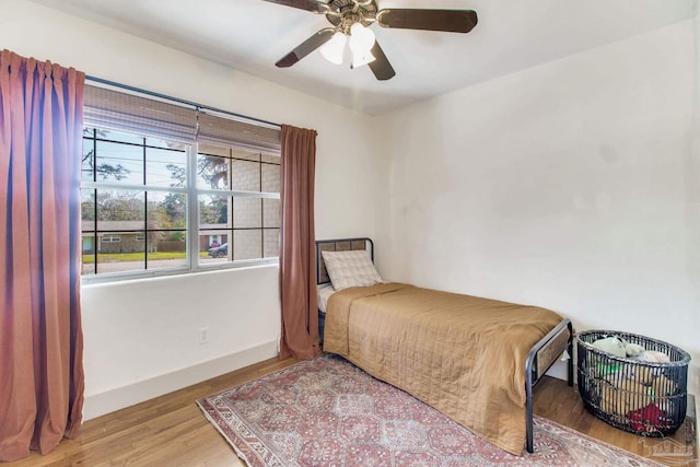 bedroom with baseboards, wood finished floors, and a ceiling fan