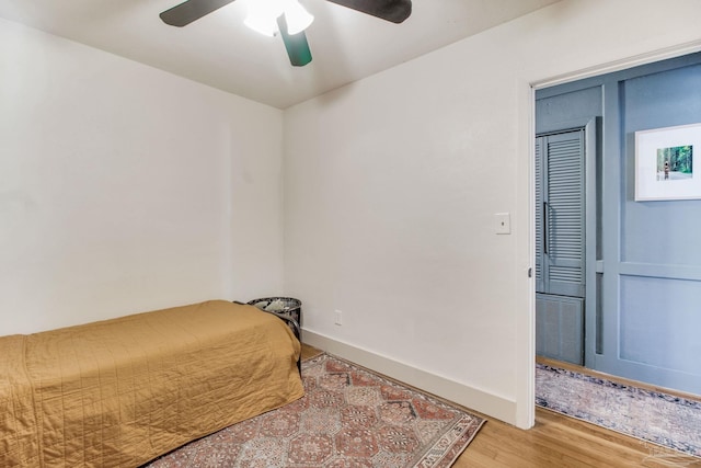 bedroom featuring a ceiling fan, baseboards, and wood finished floors