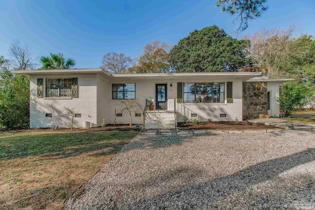 single story home featuring crawl space, a front yard, and brick siding