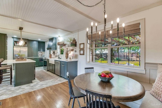 dining space with wood ceiling, a wainscoted wall, light wood-style floors, and an inviting chandelier