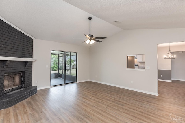 10104 Clearsound Dr, Pensacola, FL 32506 - unfurnished living room featuring vaulted ceiling, light wood-style flooring, a brick fireplace, and ceiling fan with notable chandelier