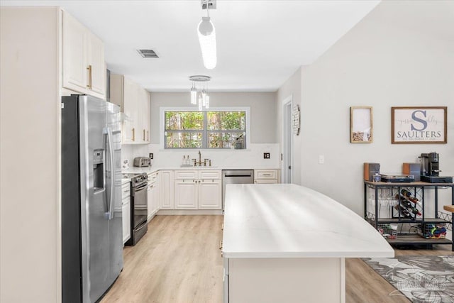 4308 Northpointe Way, Pensacola, FL 32514 - kitchen with stainless steel appliances, light wood-style flooring, light countertops, a kitchen island, and hanging light fixtures