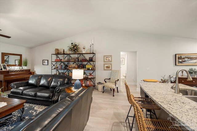 living area with vaulted ceiling, light wood-style flooring, and a ceiling fan