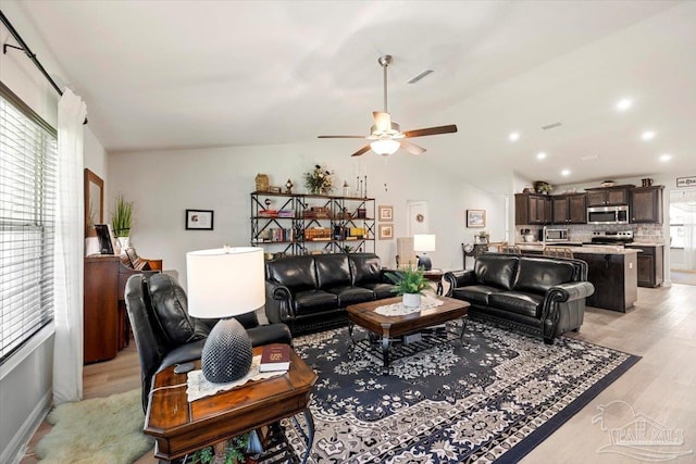 living room featuring lofted ceiling, light wood-style floors, and ceiling fan