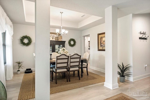 dining room with light wood-style floors, a chandelier, baseboards, and a tray ceiling