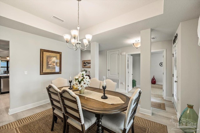dining space with light wood-type flooring, a chandelier, and baseboards