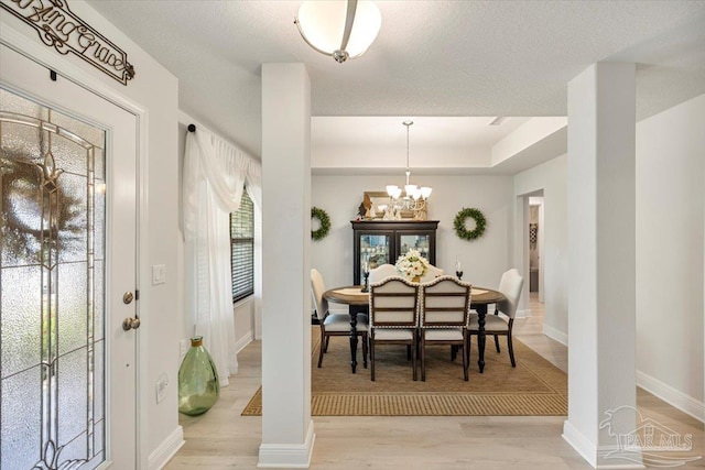 dining area featuring a chandelier, light wood-style flooring, and baseboards