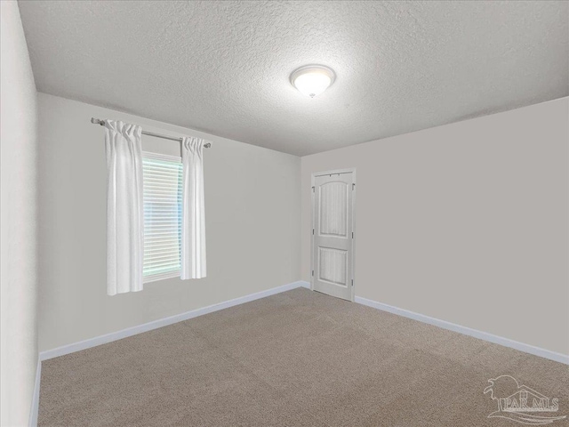 unfurnished room featuring a textured ceiling, light colored carpet, and baseboards