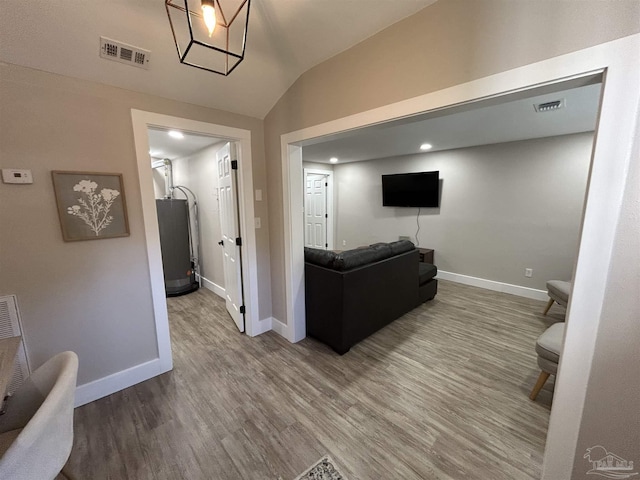 living room with hardwood / wood-style flooring, lofted ceiling, and water heater