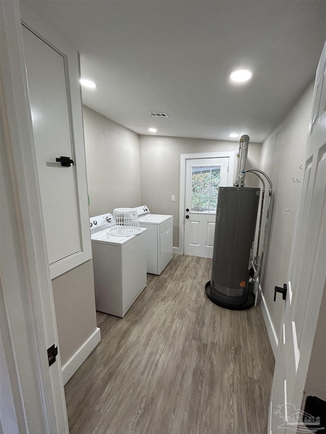 washroom featuring hardwood / wood-style flooring, gas water heater, and washing machine and dryer