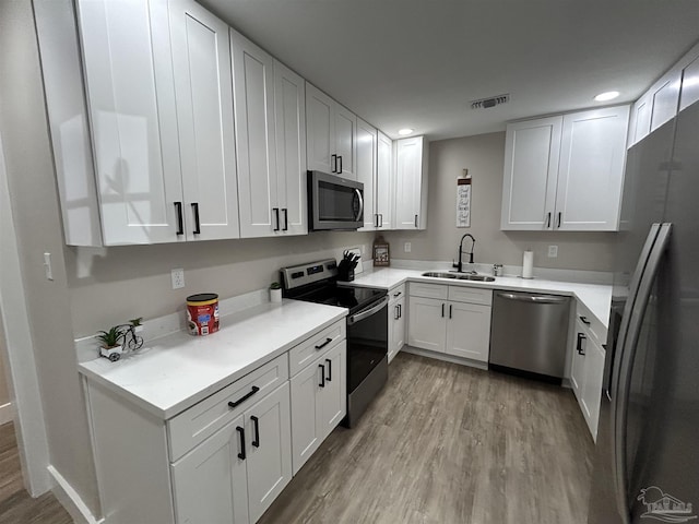 kitchen with white cabinetry, sink, appliances with stainless steel finishes, and light hardwood / wood-style flooring