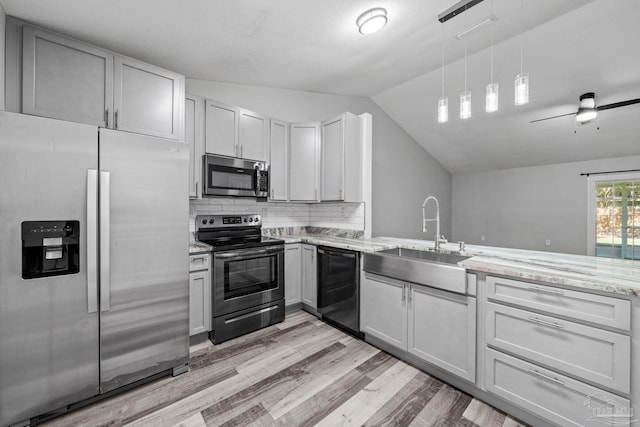 kitchen with pendant lighting, sink, light hardwood / wood-style flooring, stainless steel appliances, and vaulted ceiling