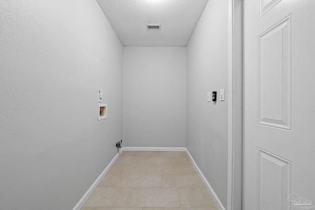 laundry area with a textured ceiling, hookup for a washing machine, and light tile patterned floors