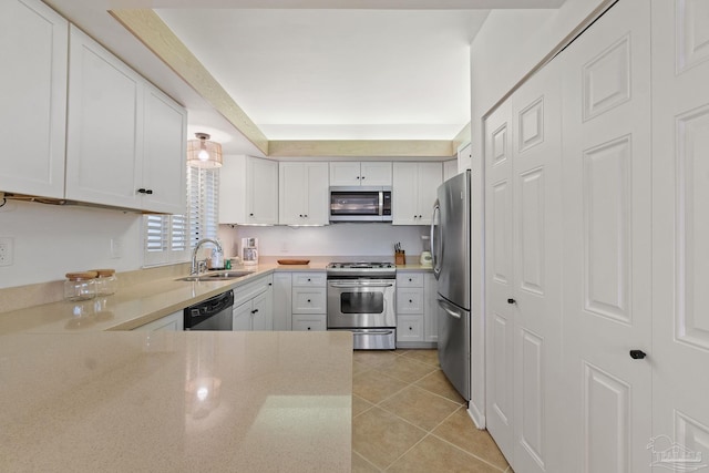 kitchen featuring light tile patterned floors, light stone counters, stainless steel appliances, a sink, and white cabinetry