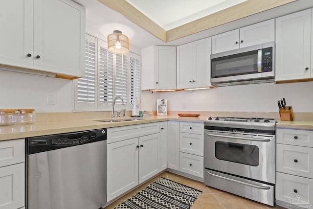 kitchen featuring light countertops, appliances with stainless steel finishes, white cabinets, a sink, and light tile patterned flooring