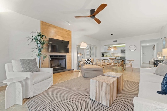 living room with a fireplace, baseboards, a ceiling fan, and light tile patterned flooring