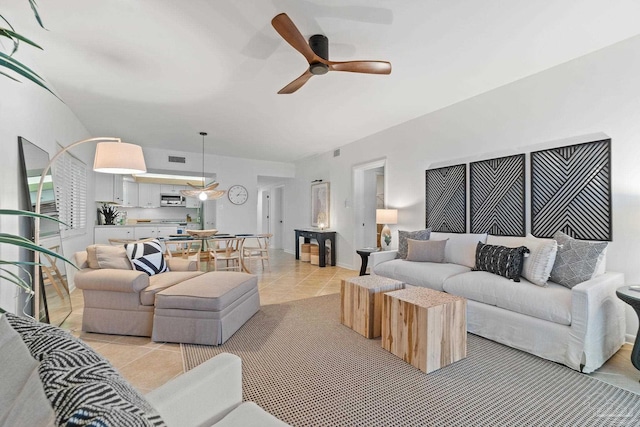 living area featuring a ceiling fan, baseboards, and light tile patterned floors