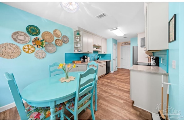7837 Skyview Blvd, Navarre, FL 32566 - kitchen with black dishwasher, light wood finished floors, open shelves, and tasteful backsplash