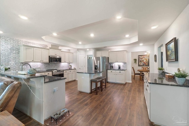 2849 Pga Blvd, Navarre, FL 32566 - kitchen with appliances with stainless steel finishes, a raised ceiling, a breakfast bar, a peninsula, and recessed lighting