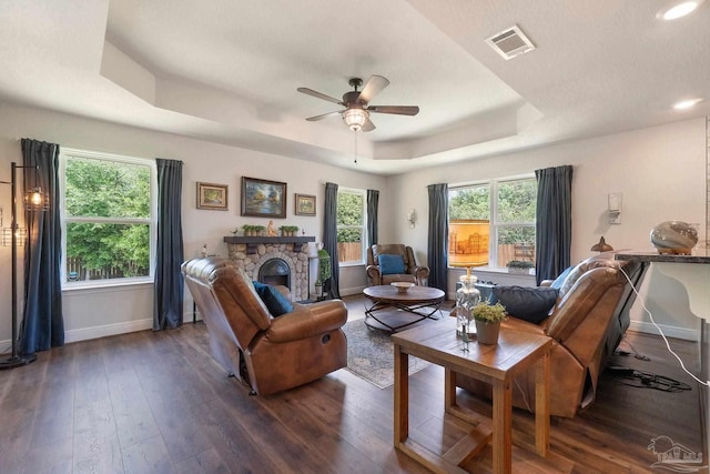 2849 Pga Blvd, Navarre, FL 32566 - living area featuring a raised ceiling, baseboards, a ceiling fan, dark wood finished floors, and a stone fireplace