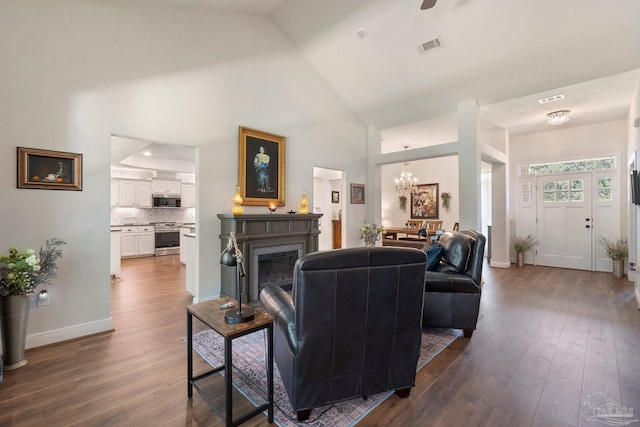 2849 Pga Blvd, Navarre, FL 32566 - living area featuring dark wood-type flooring, a chandelier, high vaulted ceiling, a glass covered fireplace, and baseboards
