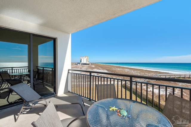 balcony featuring a view of the beach and a water view