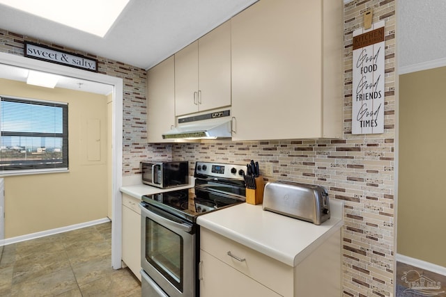 kitchen with a textured ceiling, cream cabinetry, and stainless steel range with electric stovetop