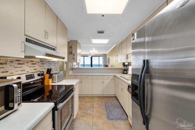 kitchen featuring cream cabinetry, stainless steel appliances, tasteful backsplash, a chandelier, and sink