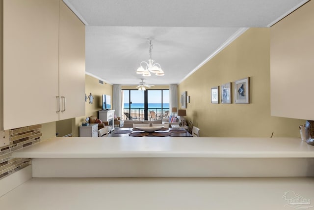 kitchen featuring crown molding, pendant lighting, ceiling fan with notable chandelier, and kitchen peninsula