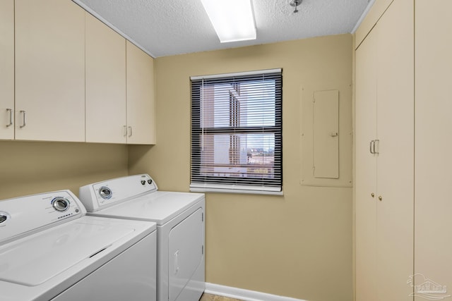 laundry area with washer and dryer, cabinets, a textured ceiling, and electric panel