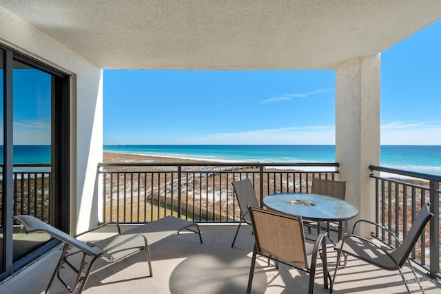 balcony with a water view and a view of the beach