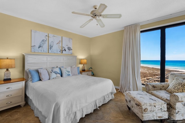 bedroom featuring ceiling fan, a beach view, multiple windows, and a water view