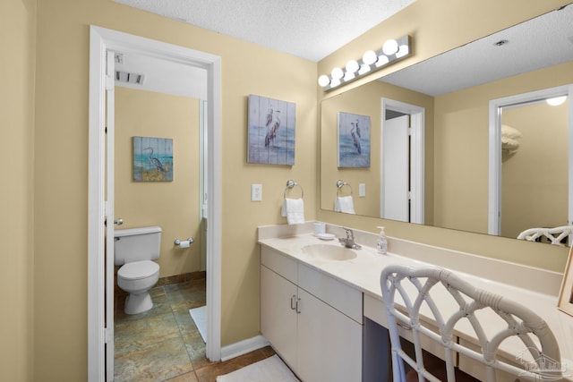 bathroom with toilet, vanity, and a textured ceiling