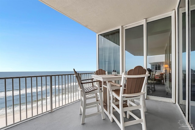 balcony with a water view and a view of the beach