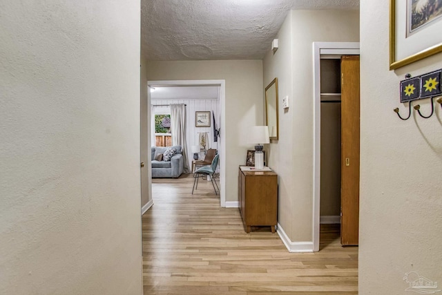 hallway featuring light hardwood / wood-style floors and a textured ceiling