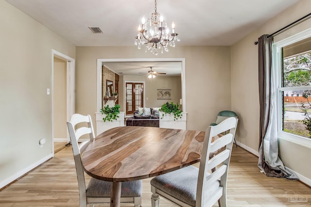 dining area with ceiling fan with notable chandelier and light hardwood / wood-style flooring