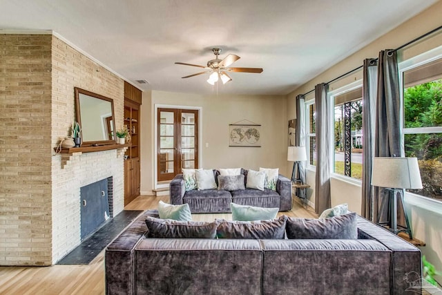 living room featuring french doors, a fireplace, ceiling fan, and light hardwood / wood-style flooring