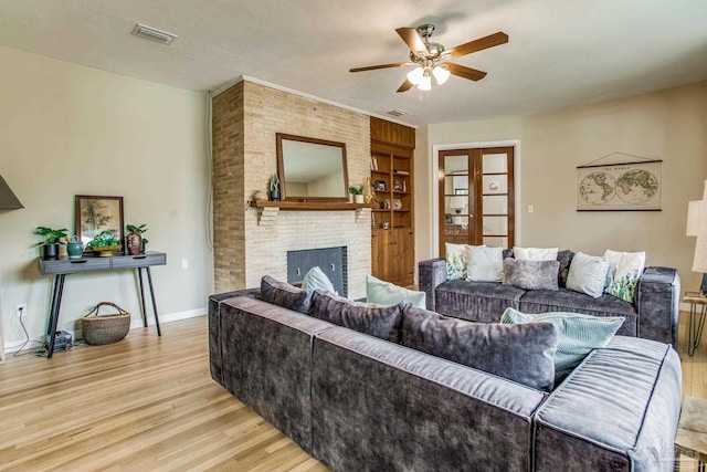 living room with ceiling fan, a fireplace, and light hardwood / wood-style flooring