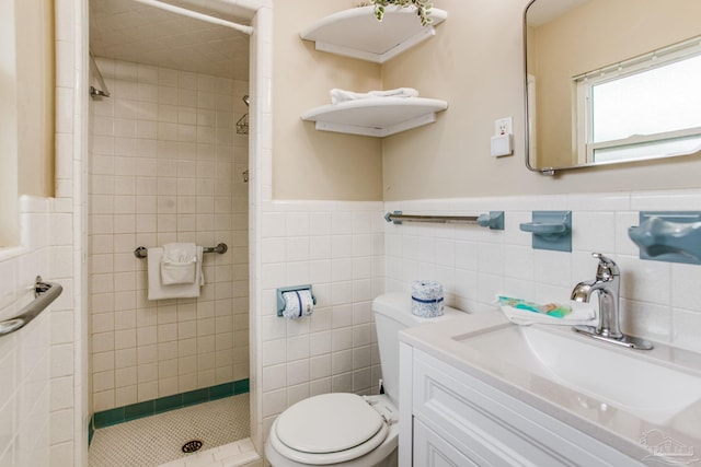 bathroom with tiled shower, vanity, toilet, and tile walls