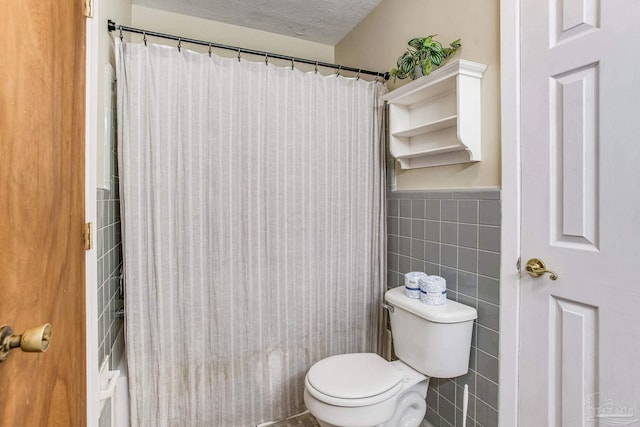 bathroom featuring a shower with shower curtain, tile walls, a textured ceiling, and toilet