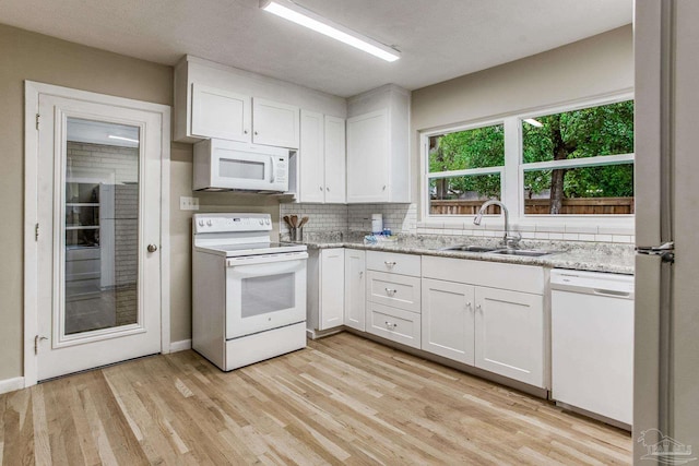 kitchen with sink, light stone counters, light hardwood / wood-style flooring, white appliances, and white cabinets