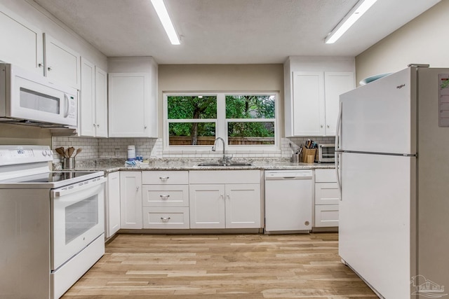 kitchen featuring white cabinetry, sink, white appliances, and light hardwood / wood-style flooring