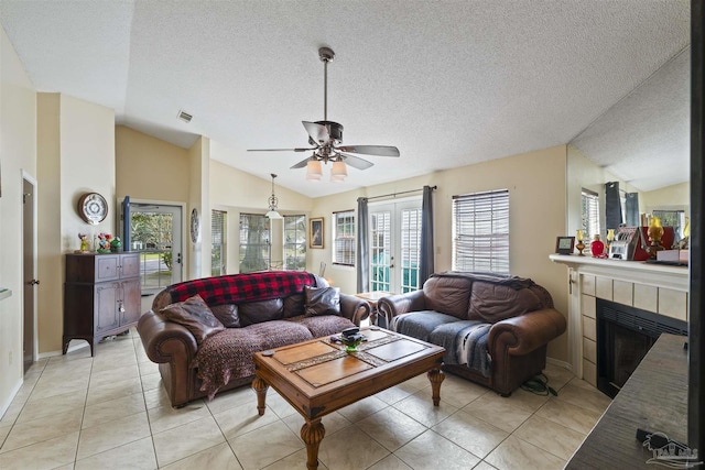 living room with french doors, vaulted ceiling, a textured ceiling, light tile patterned floors, and a tile fireplace