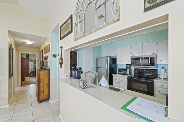kitchen with light tile patterned floors, a high ceiling, white cabinets, and appliances with stainless steel finishes