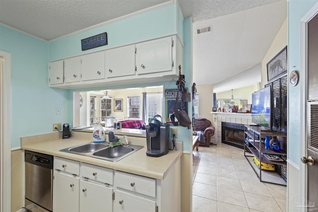 kitchen featuring sink, stainless steel dishwasher, white cabinets, and a fireplace